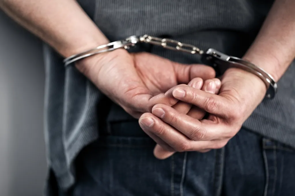 An arrested man in handcuffs with his hands behind his back.