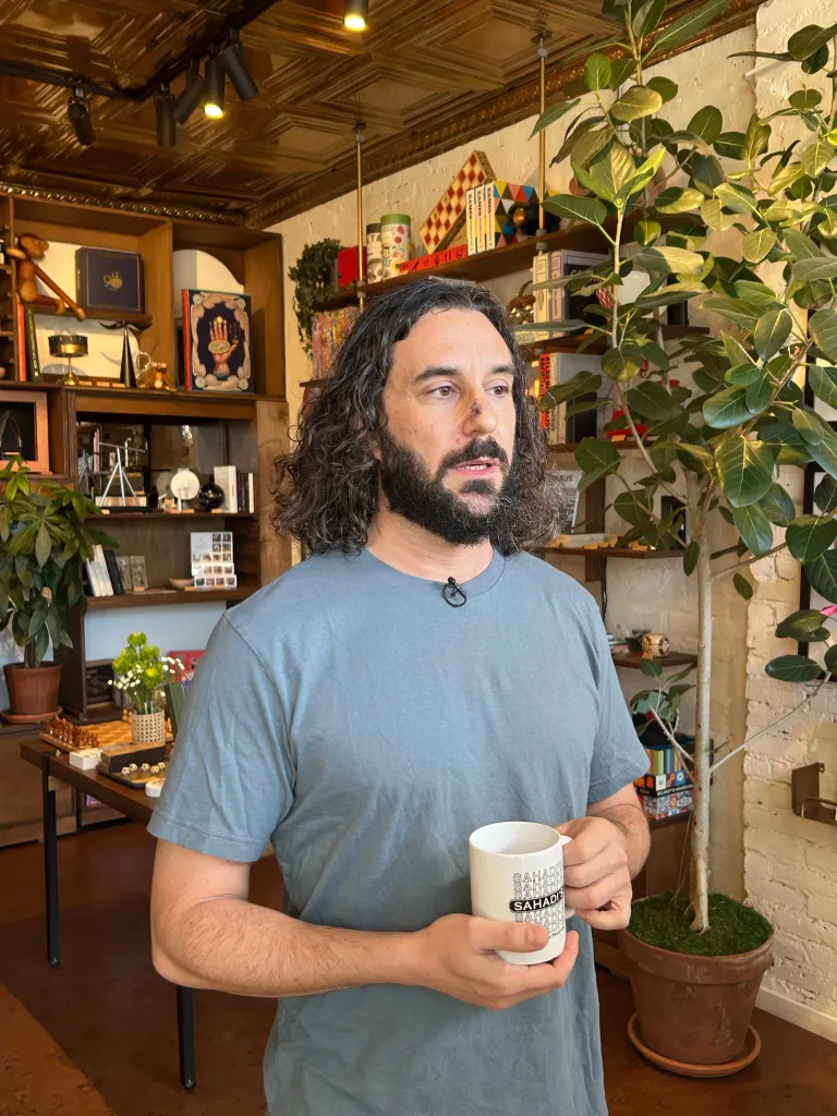 Art of Play owner Adam Rubin holding a mug inside a shop.