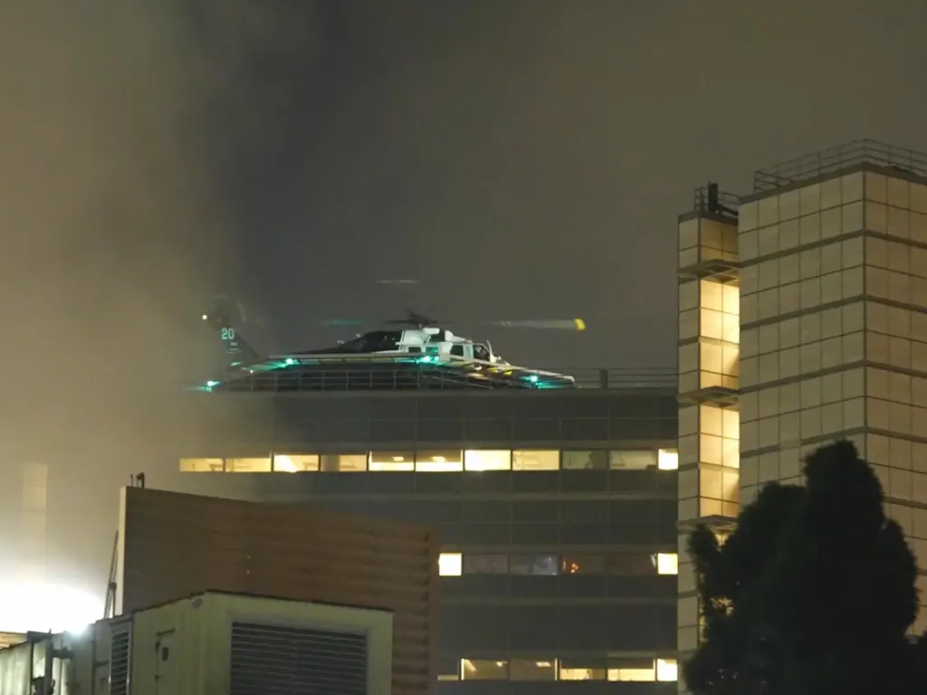 A medical helicopter on a hospital rooftop at night.