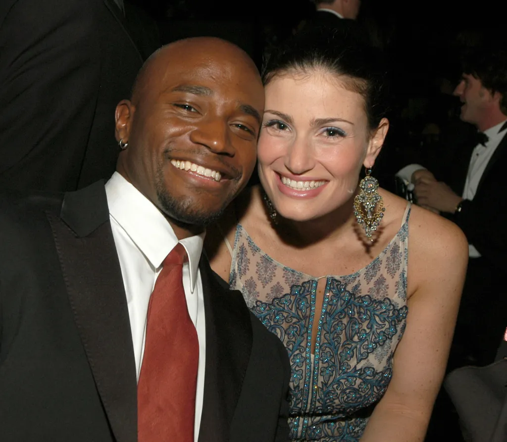 Taye Diggs and Idina Menzel pose backstage, smiling closely together.
