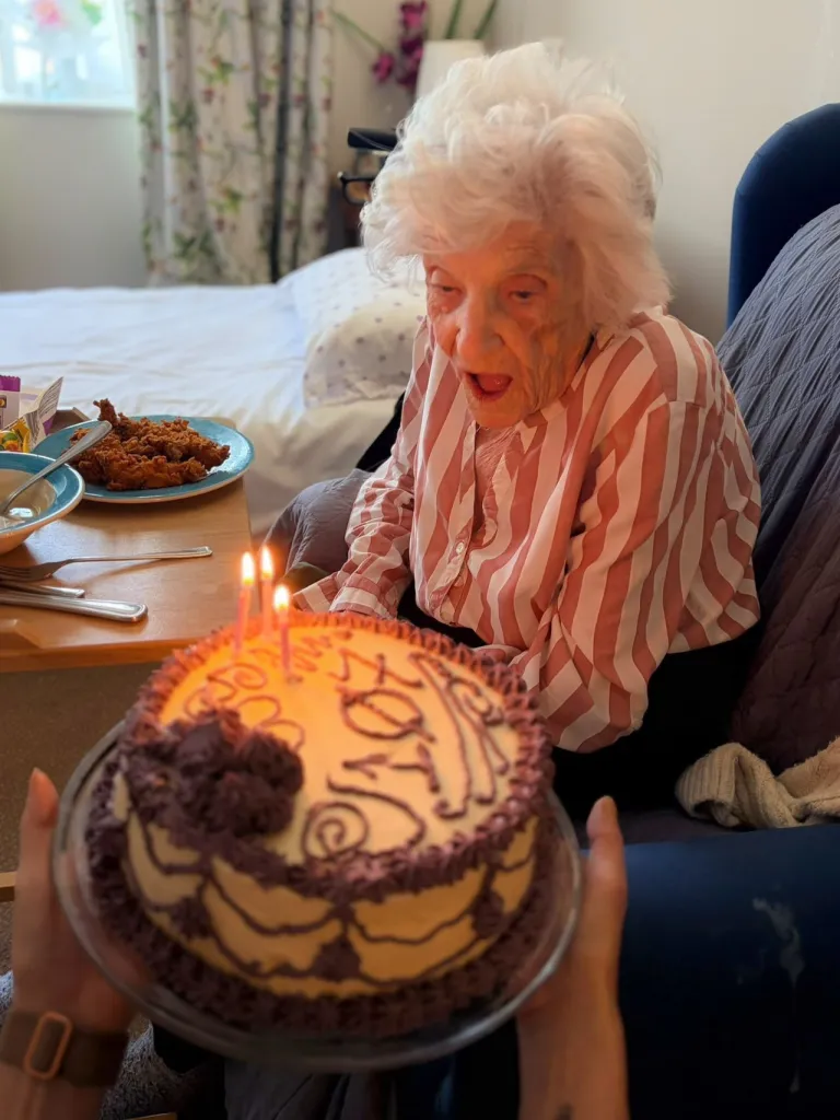 Dorothy Creighton celebrating her 107th birthday with a cake featuring lit candles.