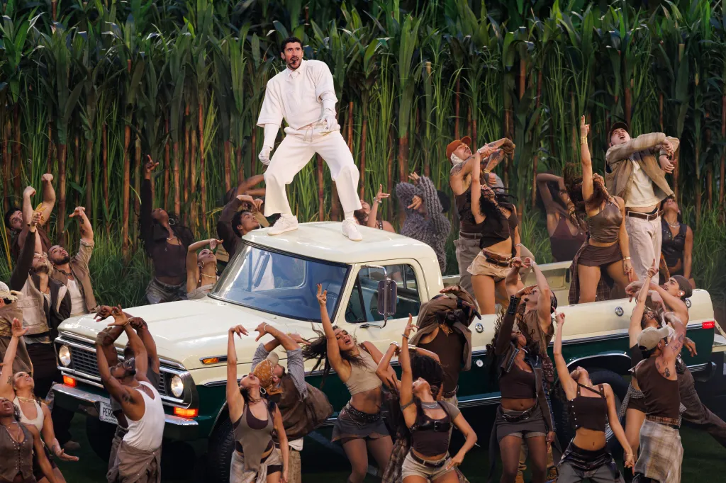 Bad Bunny performs during the Apple Music Super Bowl LX Halftime Show, standing atop a white and green pickup truck, surrounded by dancers.