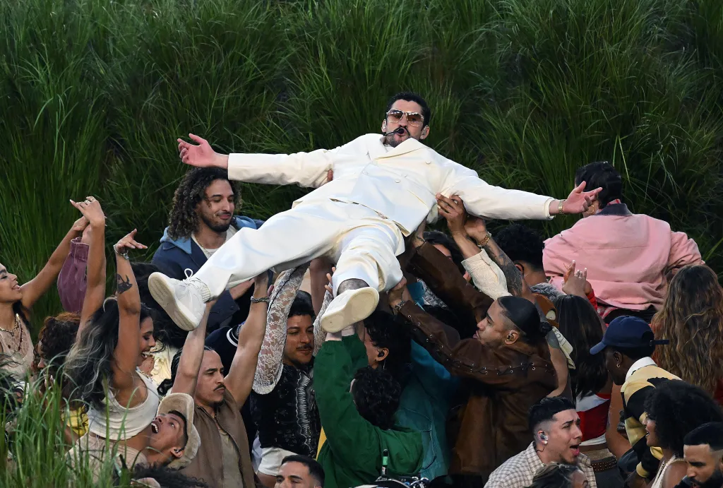 Bad Bunny crowd-surfs in a white suit during his Super Bowl Halftime Show performance.