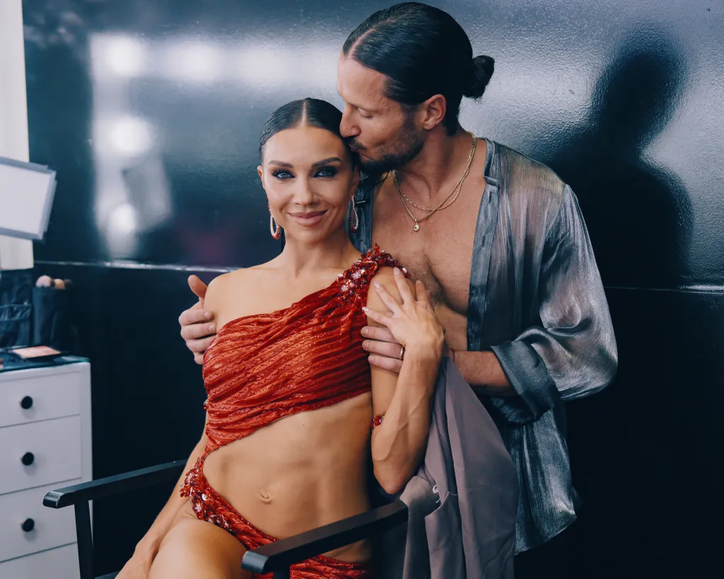 Jenna Johnson and Valentin Chmerkovskiy pose backstage, with Valentin kissing Jenna on the head.