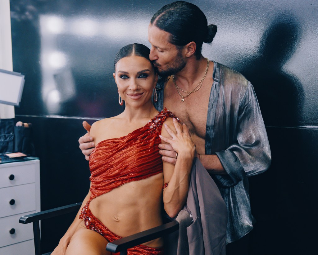 Jenna Johnson and Valentin Chmerkovskiy embrace backstage, with Valentin kissing Jenna on the cheek.