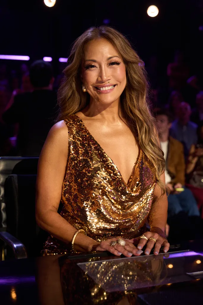Carrie Ann Inaba wearing a gold sequin dress at the judges' table on Dancing with the Stars.