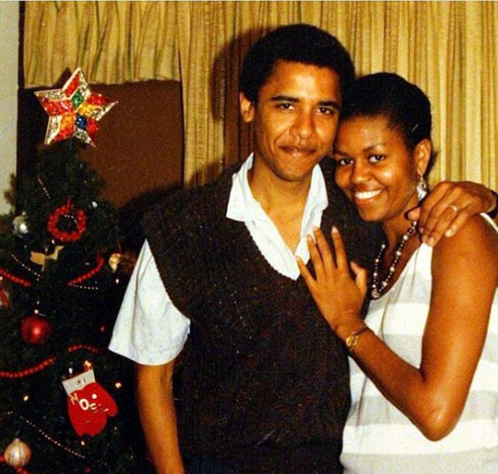 Barack and Michelle Obama posing together next to a Christmas tree.