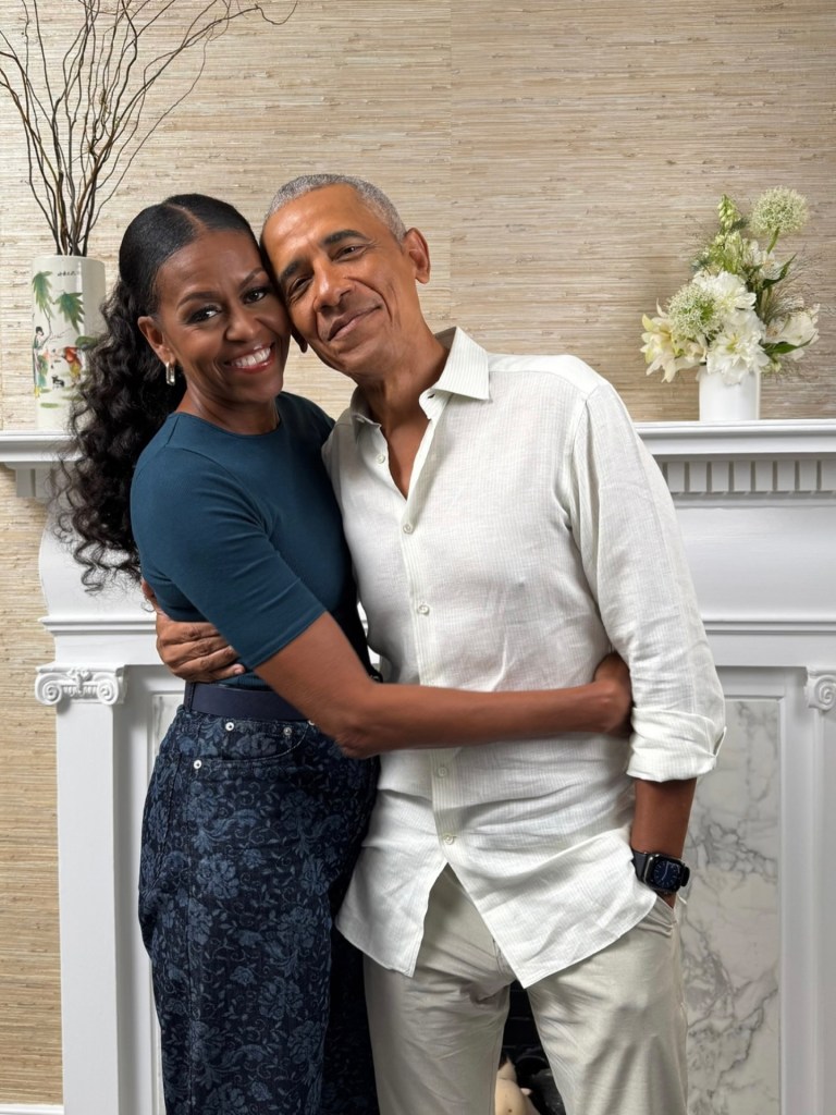 Michelle Obama and Barack Obama embracing and smiling indoors.