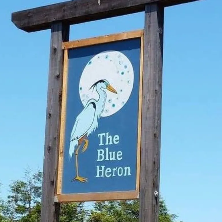 The wooden sign for The Blue Heron restaurant, featuring an illustration of a heron against a full moon.
