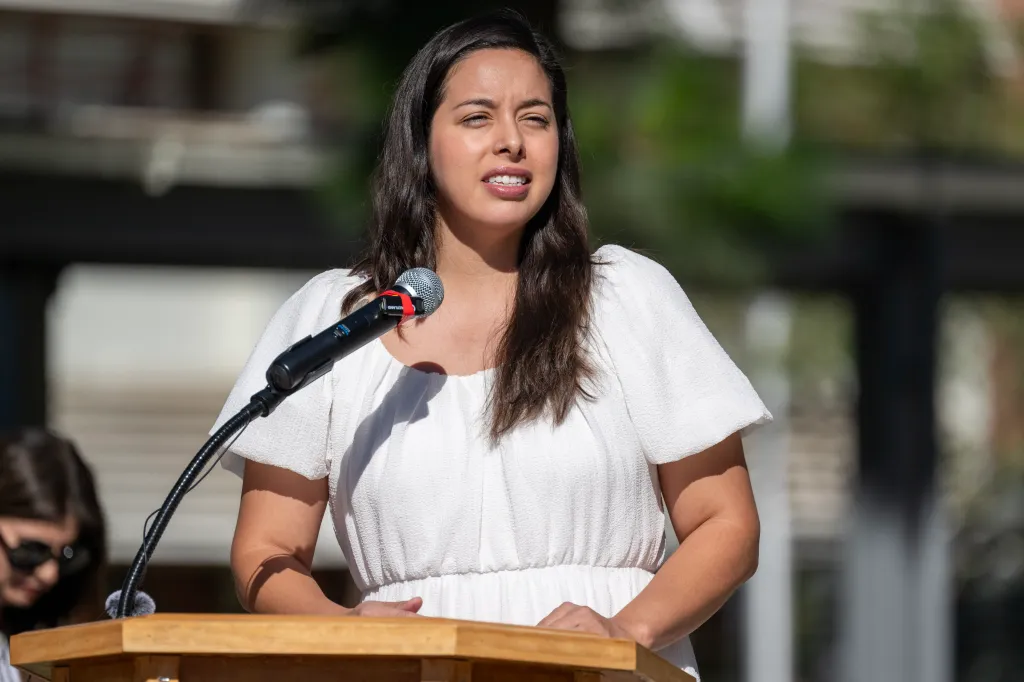 Board of Education Member Kelly Gonez speaks at a microphone during a ribbon cutting ceremony.