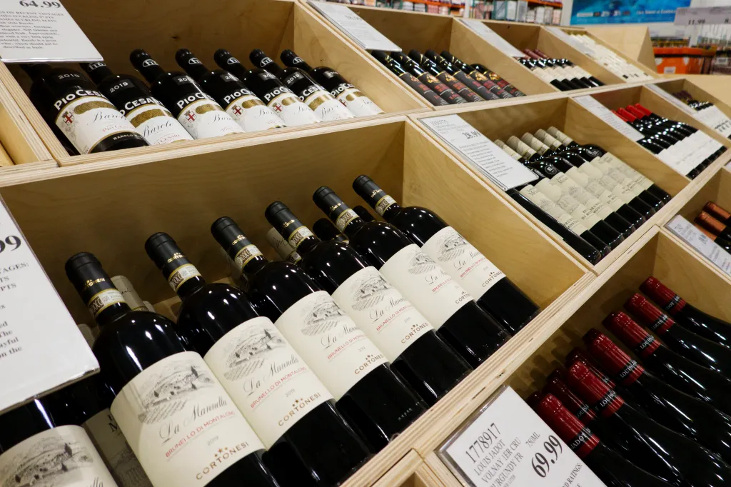 Bottles of wine displayed in wooden bins at a store.