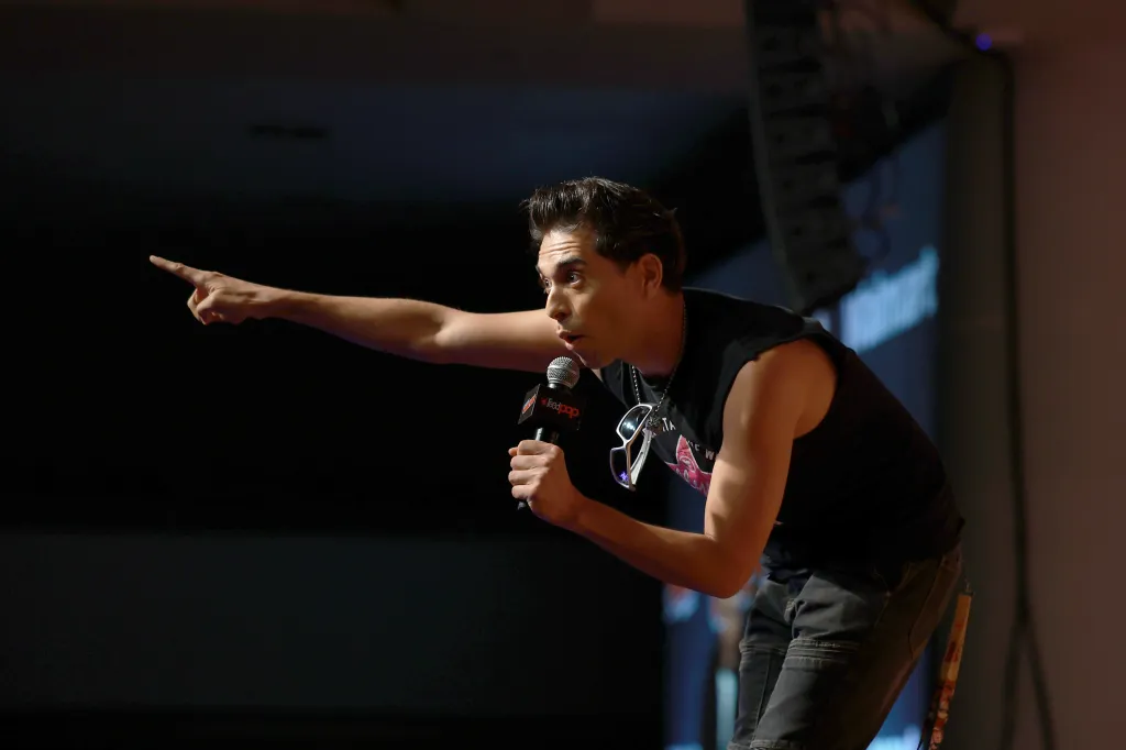 Brandon Rogers speaks into a microphone while pointing his finger.