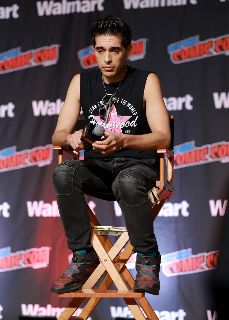 Brandon Rogers seated on stage holding a microphone in front of a New York Comic Con backdrop.