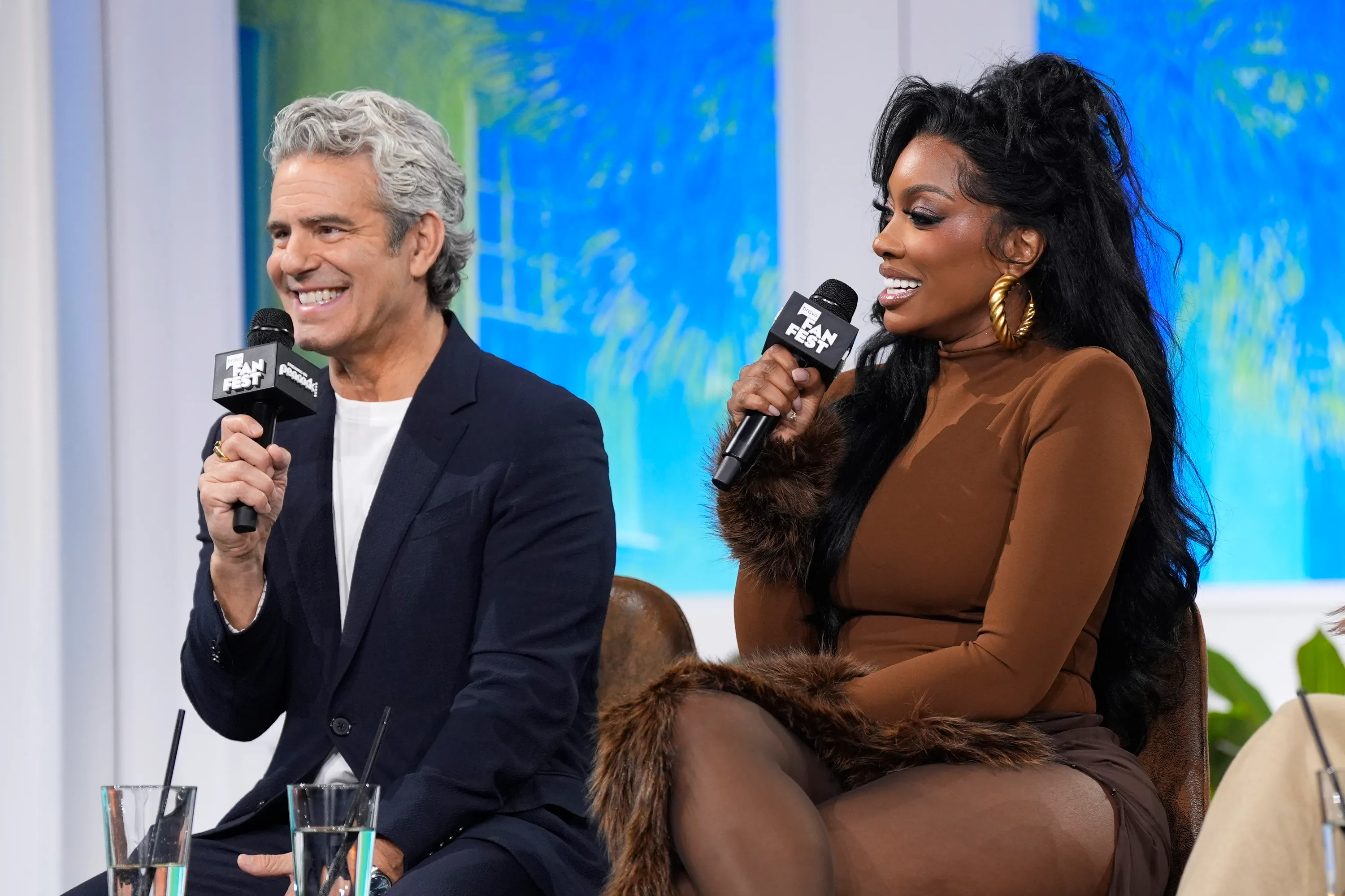 Andy Cohen and Porsha Williams speak into microphones at the Bravo Fan Fest panel.