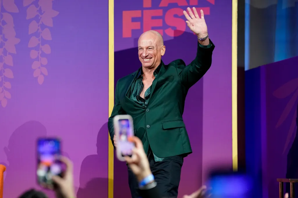 Captain Kerry Titheradge waves to the crowd at a Bravo Fan Fest panel, wearing a dark green jacket and shirt.