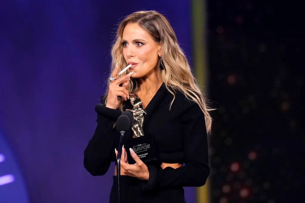 Dorit Kemsley holding a trophy while pretending to smoke a cigarette.