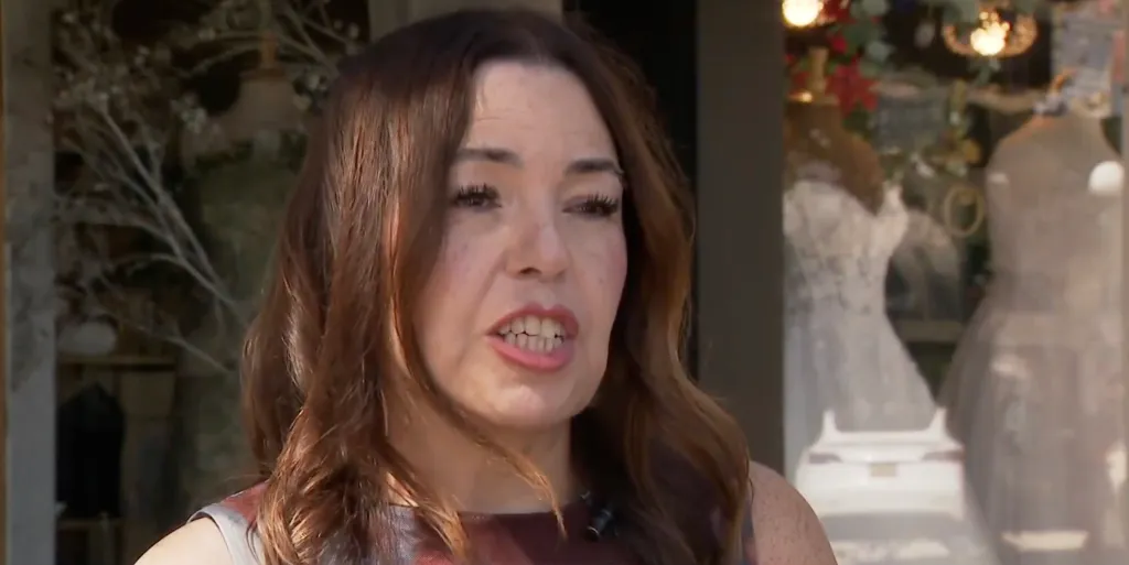 A woman speaks in front of a wedding dress shop.