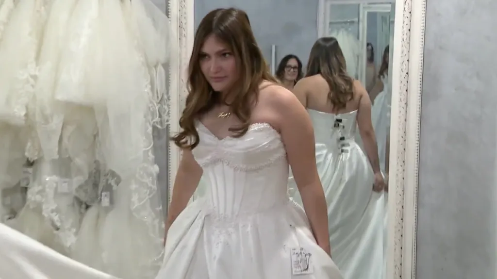 A bride-to-be tries on a white wedding dress in a bridal shop.
