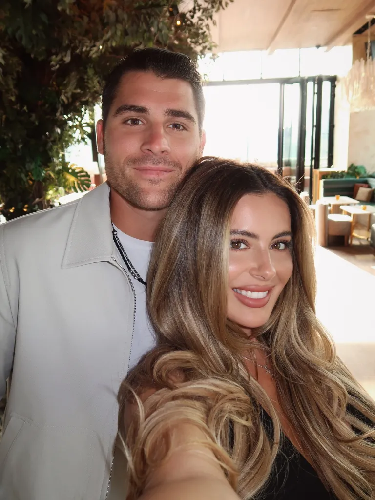 Brielle Biermann and Billy Seidl posing together indoors.