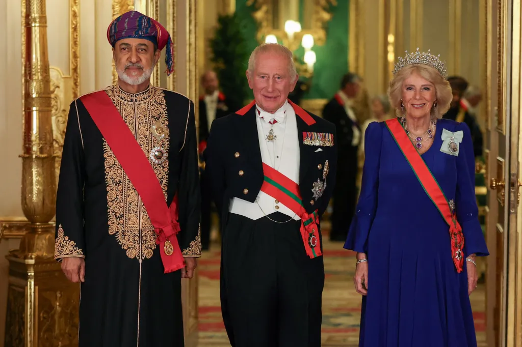 Britain's King Charles, in dress coat and tails, white waistcoat, red ash and medals, Queen Camilla, in a blue gown and red sash and medal, and Oman's Sultan Haitham bin Tariq in a black gown with gold brocade and black cap, pose for a photograph before a State Banquet at Windsor Castle.