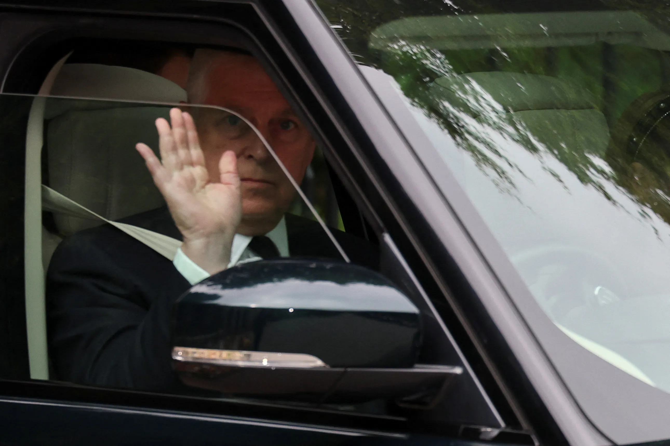 Britain's Prince Andrew waves from inside a vehicle.