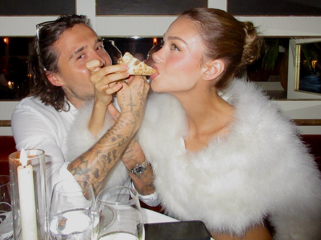 Brooklyn Beckham feeds Nicola Peltz a slice of pizza.