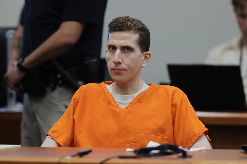 Bryan Kohberger sits at a courtroom table wearing an orange jail jumpsuit.
