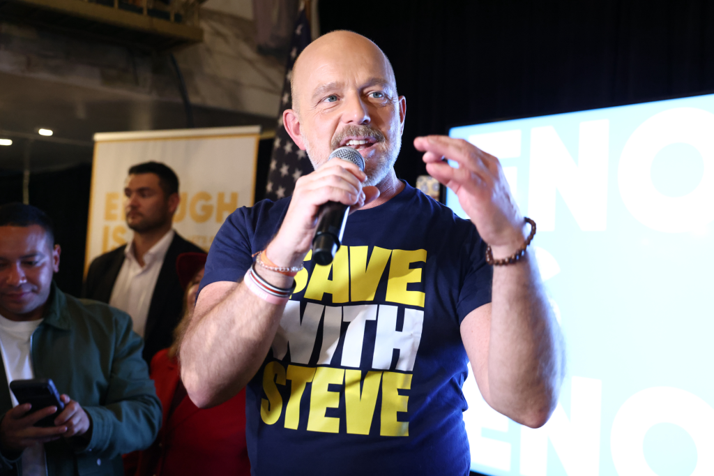 California gubernatorial candidate Steve Hilton speaks to supporters, holding a microphone and gesturing with his hand.