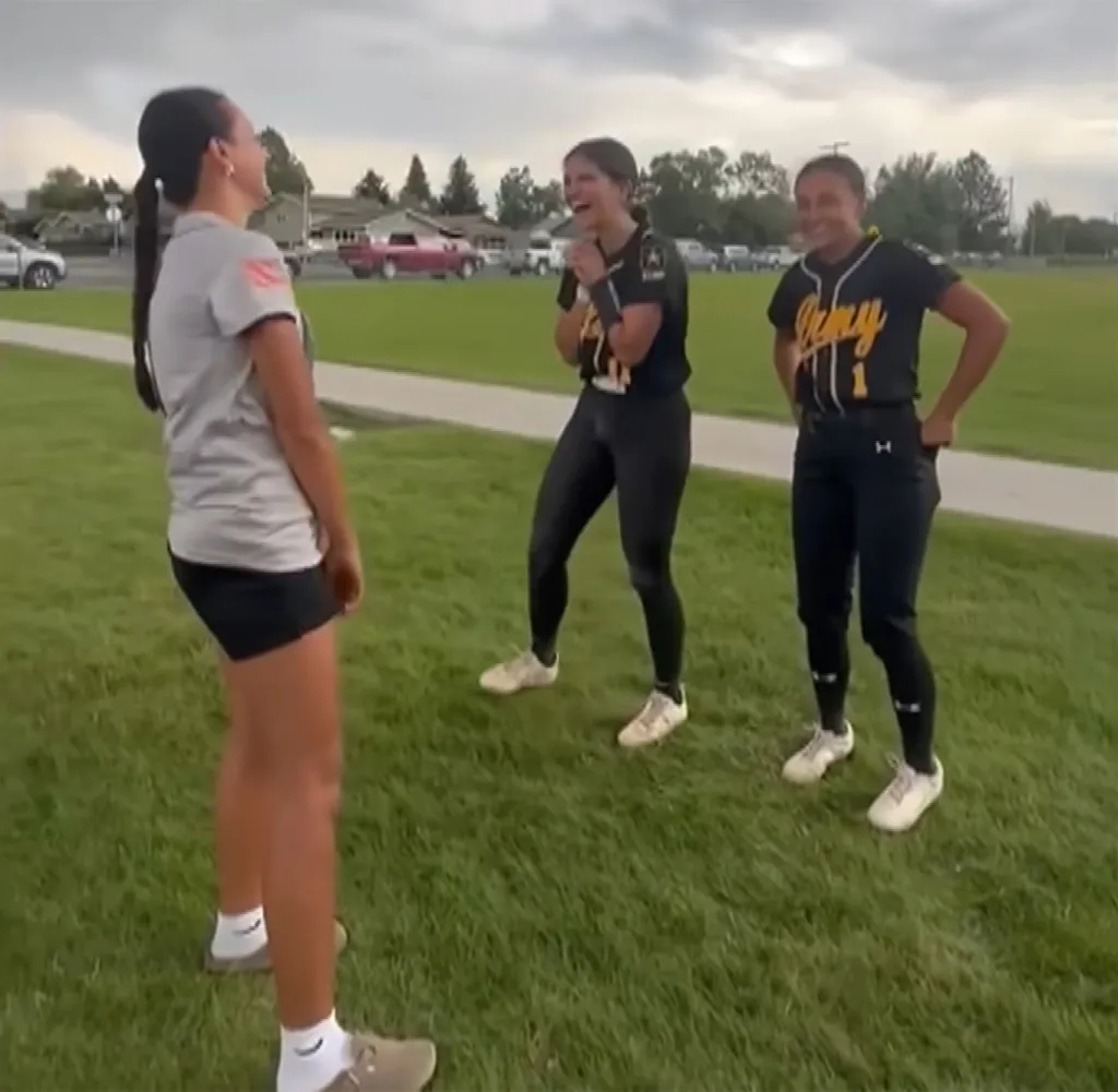 Samantha Rensvold and Kyann Dean, sisters adopted by different families, smiling and laughing together on a grassy field.