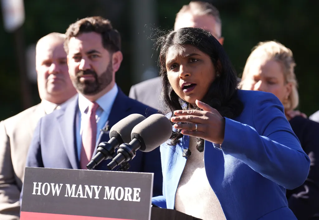 Saritha Komatireddy speaks at a press conference behind a podium that reads