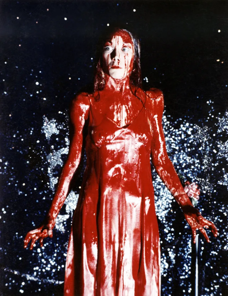 Sissy Spacek as Carrie drenched in blood on stage.