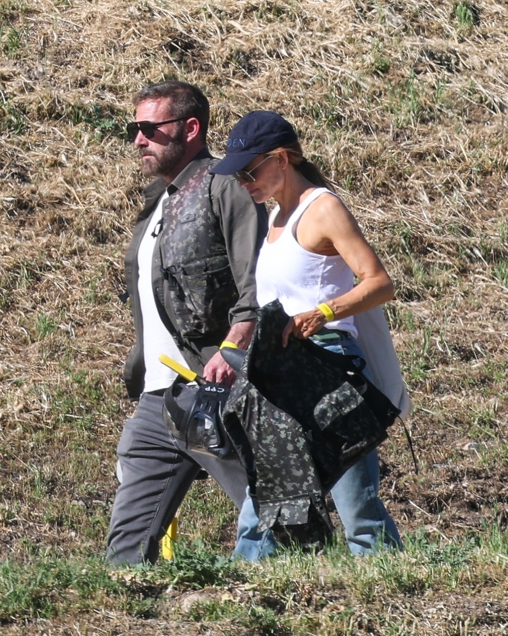 Ben Affleck and Jennifer Garner walking together outdoors, carrying paintball gear.
