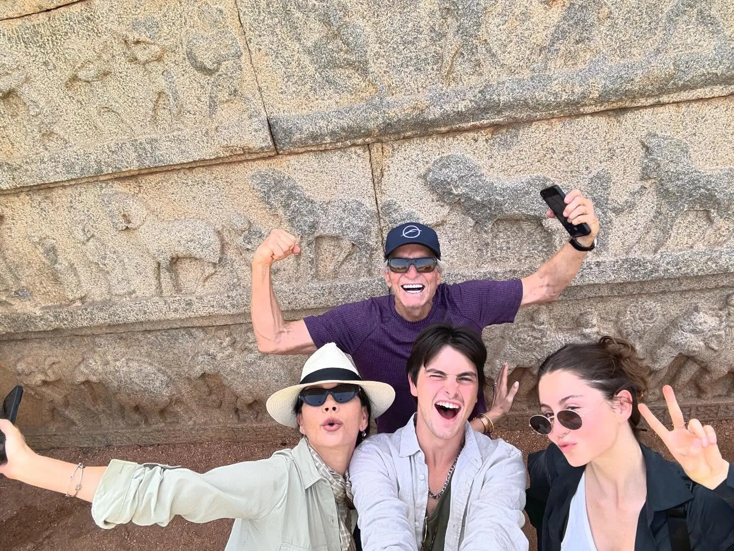 Catherine Zeta-Jones and Michael Douglas posing with Carys and Dylan in front of a stone wall.