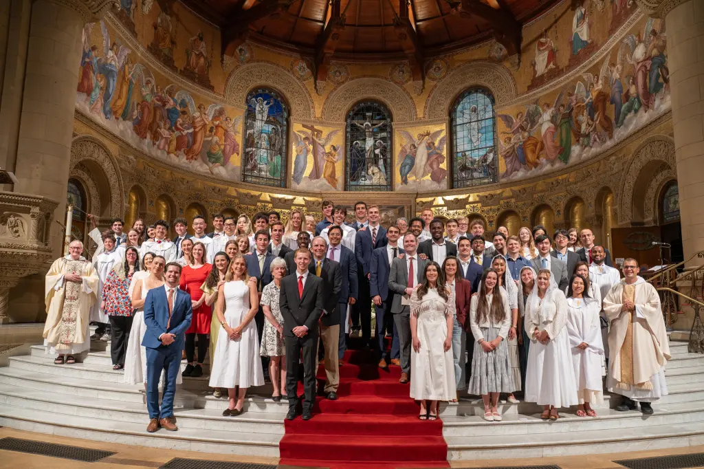 The Catholic Community at Stanford's Easter Vigil initiation class posing with their sponsors inside a church.