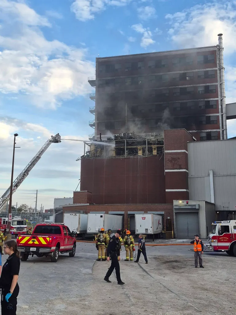 A massive fire erupts after an explosion at a Quaker Oats plant, with firefighters responding to the scene.