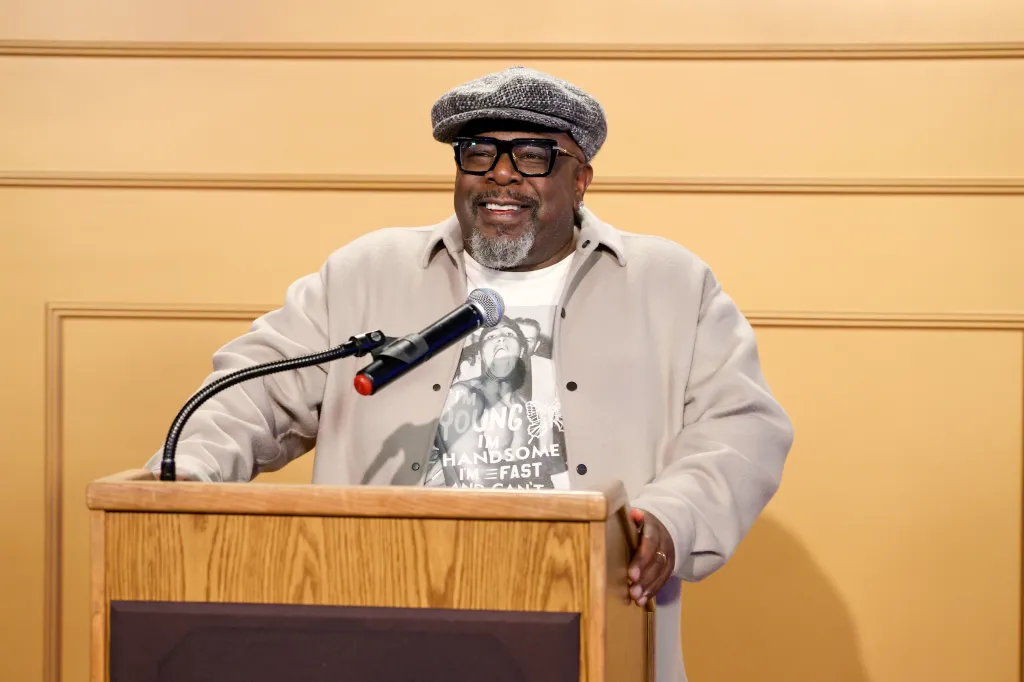 Cedric the Entertainer speaks onstage at a microphone during