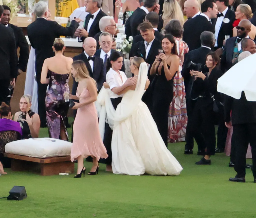 Jennifer Meyer and Courteney Cox embrace at an outdoor wedding.