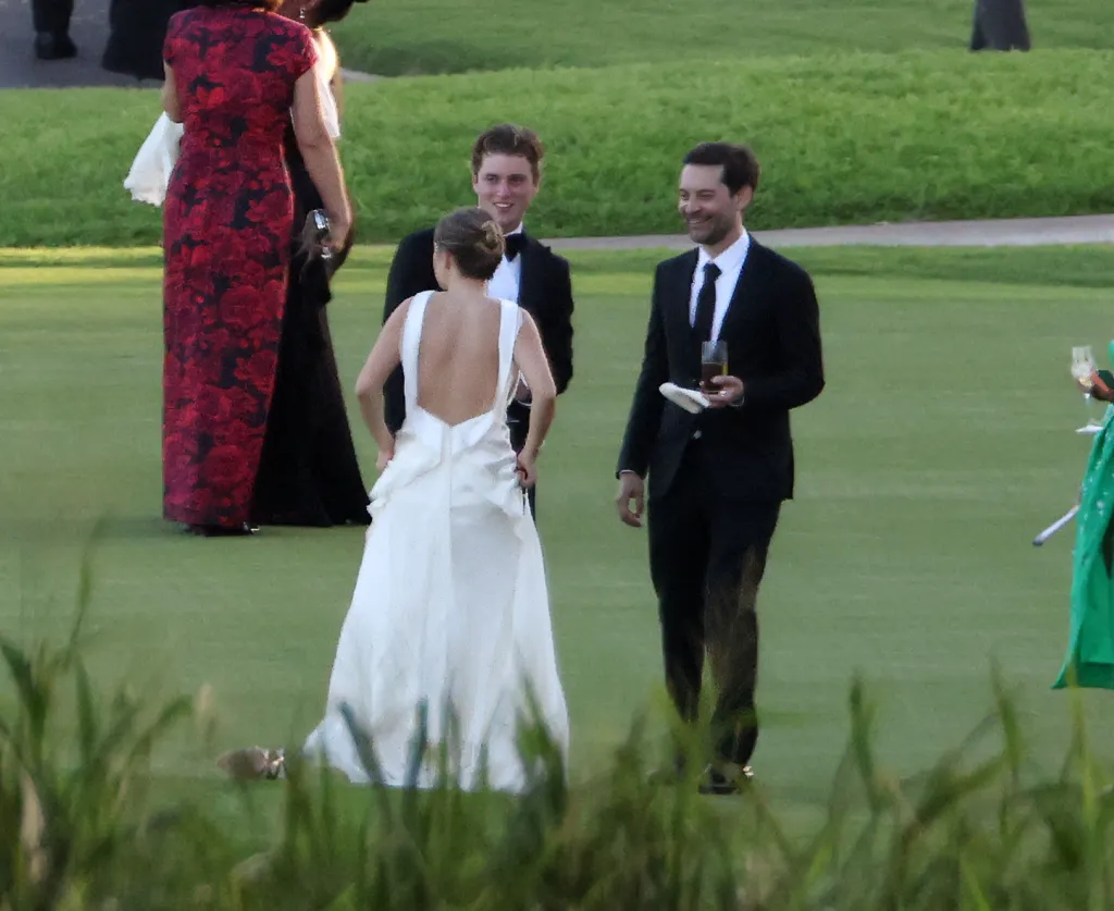 Jennifer Meyer in a white wedding dress with Geoff Ogunlesi and Tobey Maguire at their wedding in Hawaii.