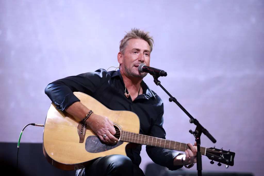 Chad Kroeger performs on stage with an acoustic guitar.