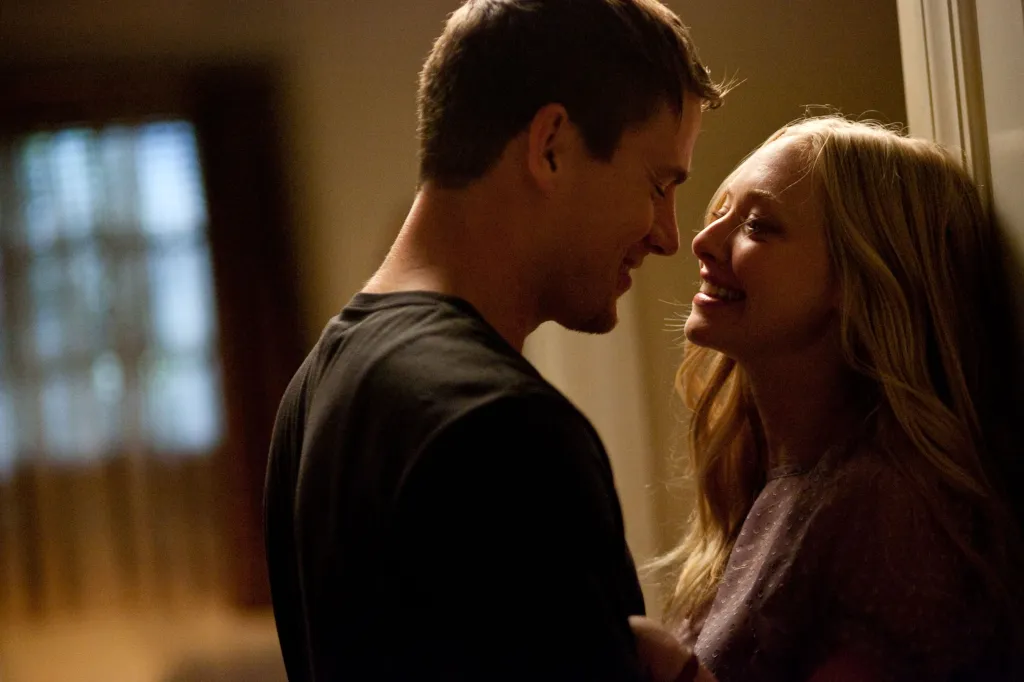 Channing Tatum and Amanda Seyfried stand face to face, smiling at each other.