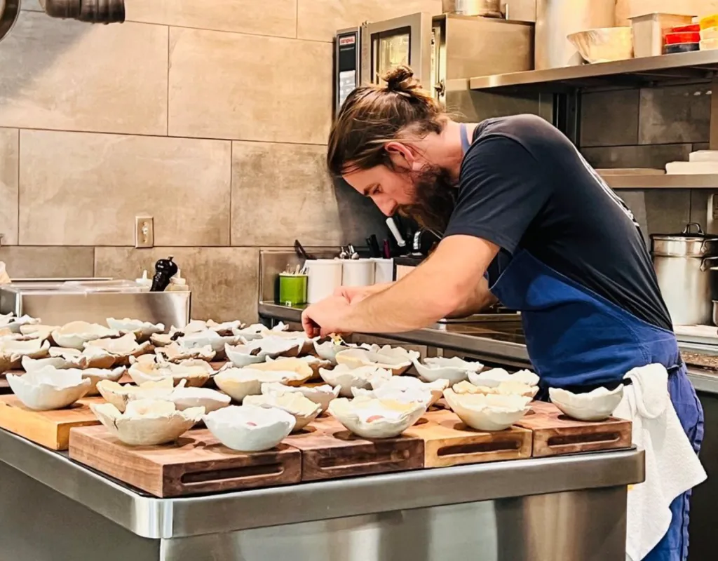 Chef Michael Warring prepares dishes in a restaurant kitchen.