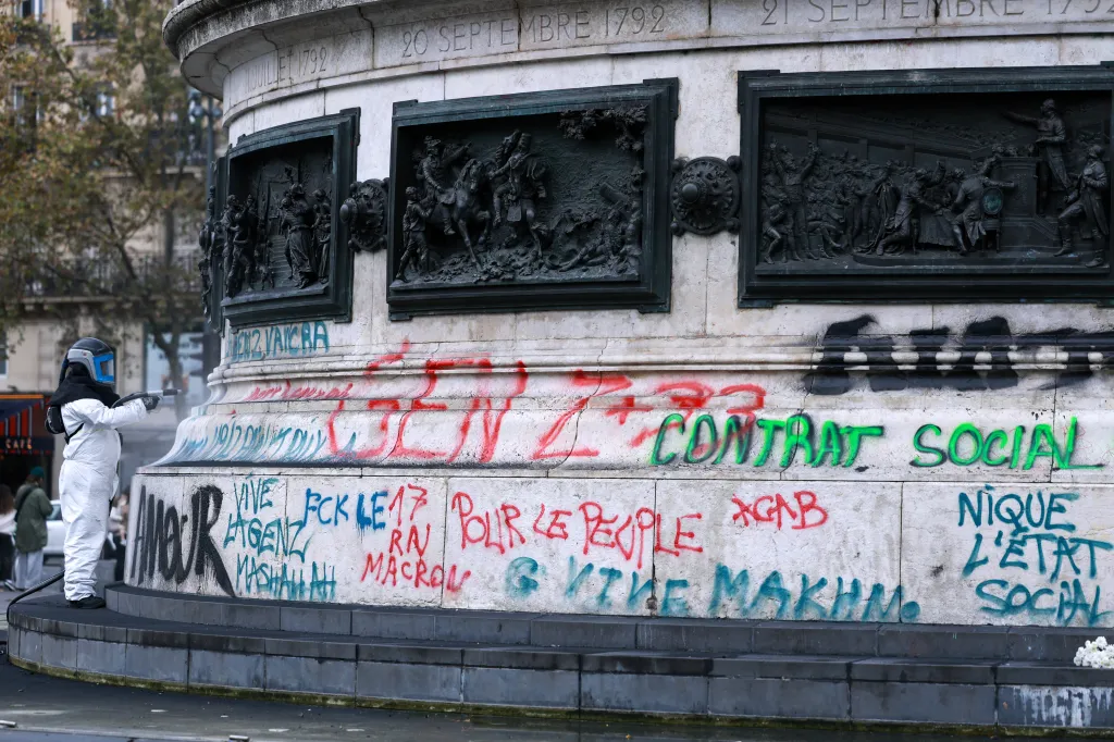 A city hall employee removes graffiti from the Place de la Republique statue.