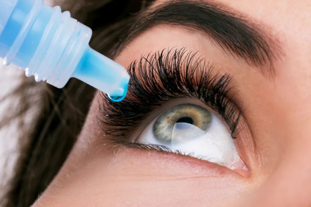 Close-up of a woman applying eye drops to her eye.