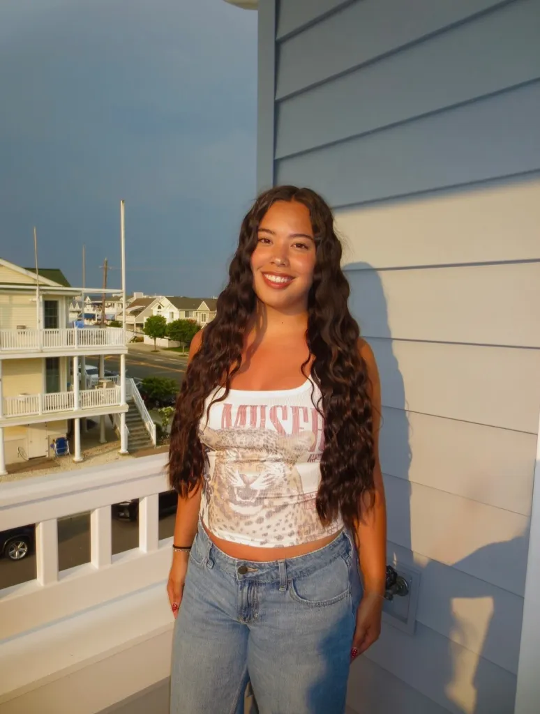 Hannah Gosselin stands on a balcony, smiling, with houses visible in the background.