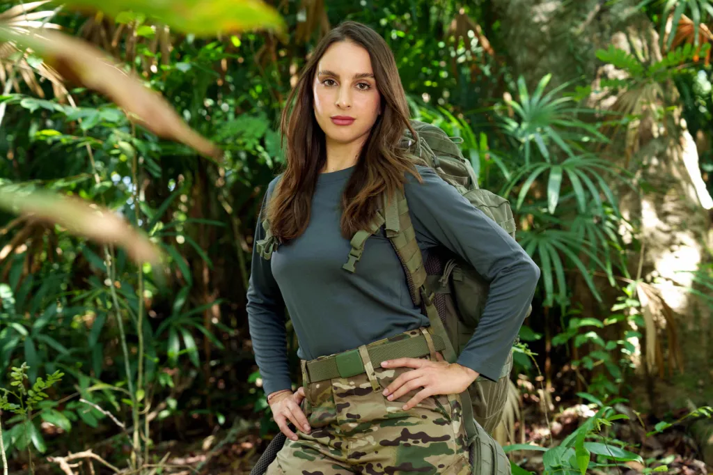 Contestant Alexia Umansky poses with a backpack in a jungle setting.