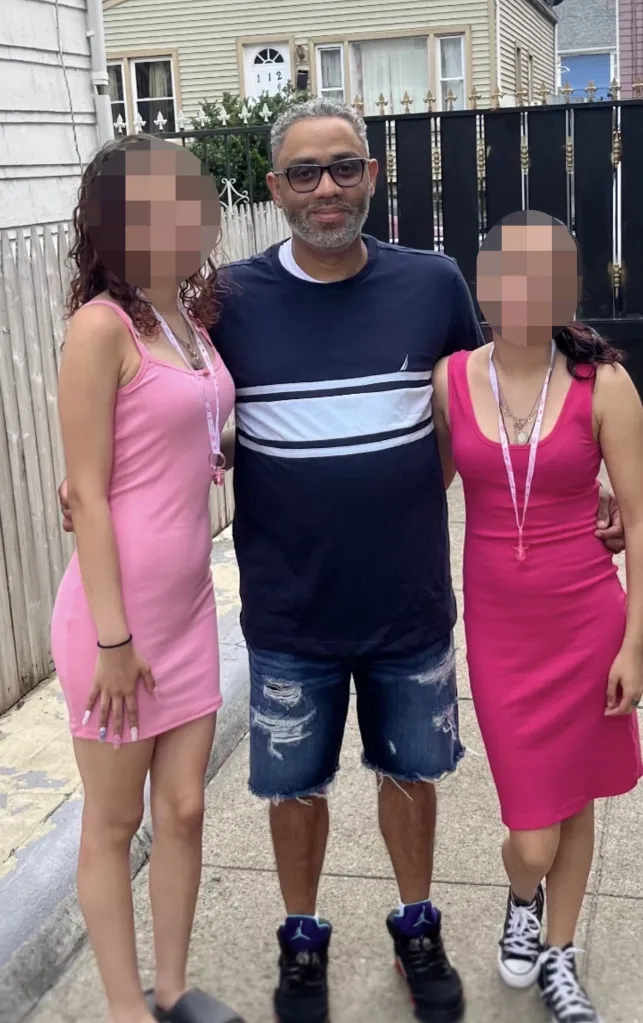 Nelson Manuel Batista standing outdoors with two young women wearing pink dresses.
