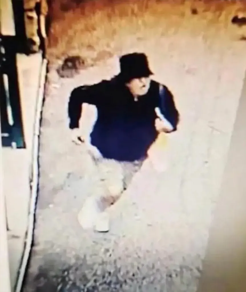 Grainy CCTV footage of Anastasiia Berezovska walking down a street wearing a dark jacket, hat, and carrying a bag.