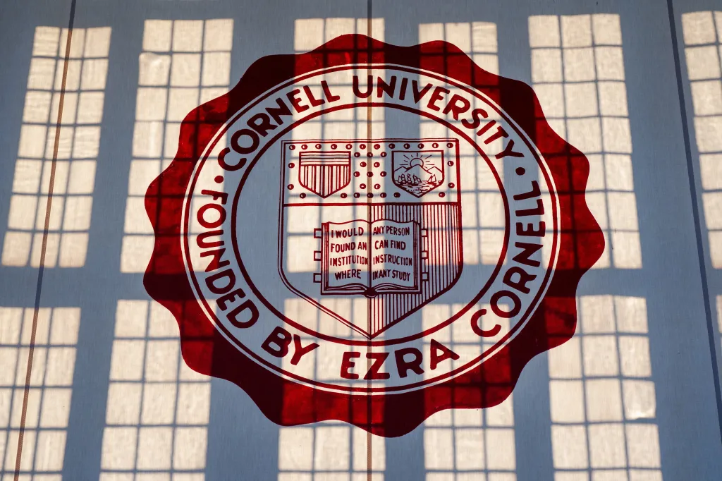 A Cornell University banner hangs in Willard Straight Hall with sunlight casting window shadows across the seal.