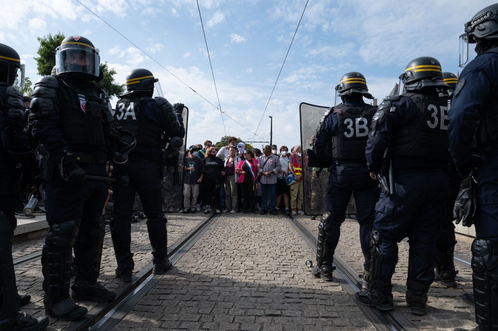 CRS riot police stand in front of demonstrators during a protest in Nantes, France.