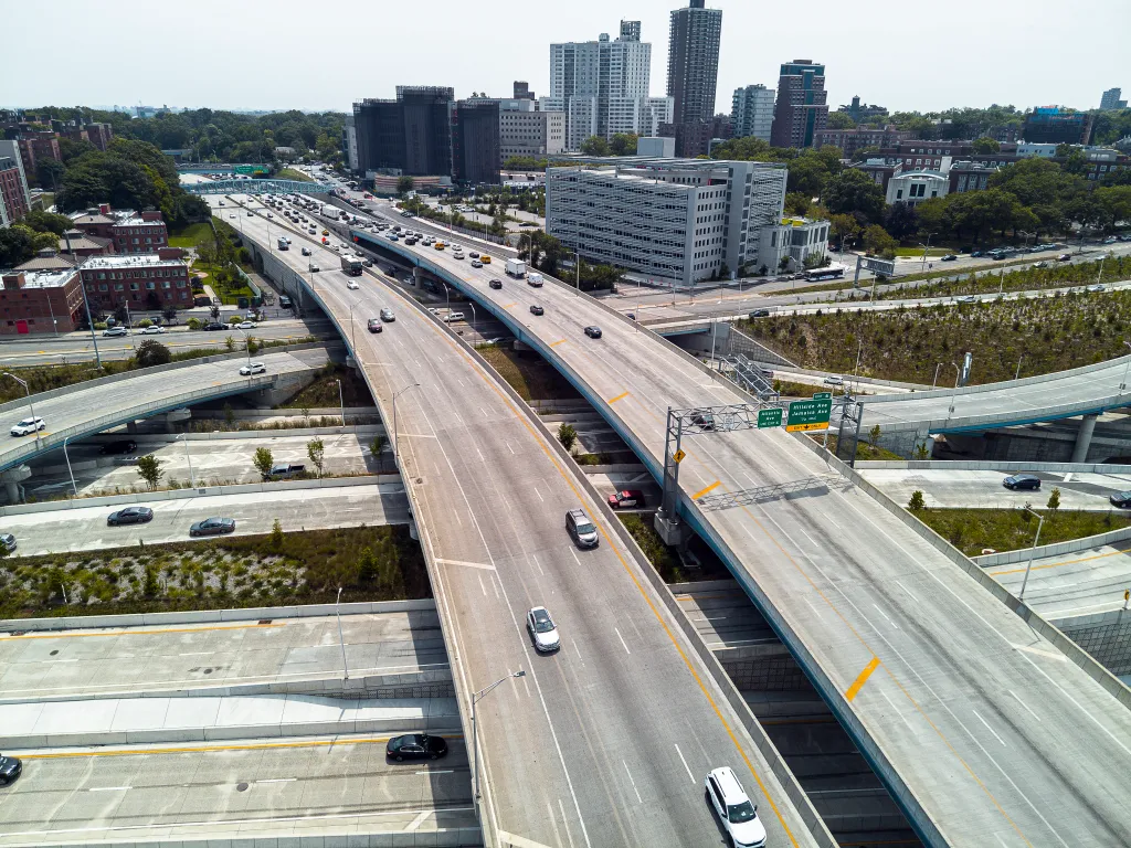 Aerial view of curvy roadways intertwining above the houses and parks of the Queens borough of New York.
